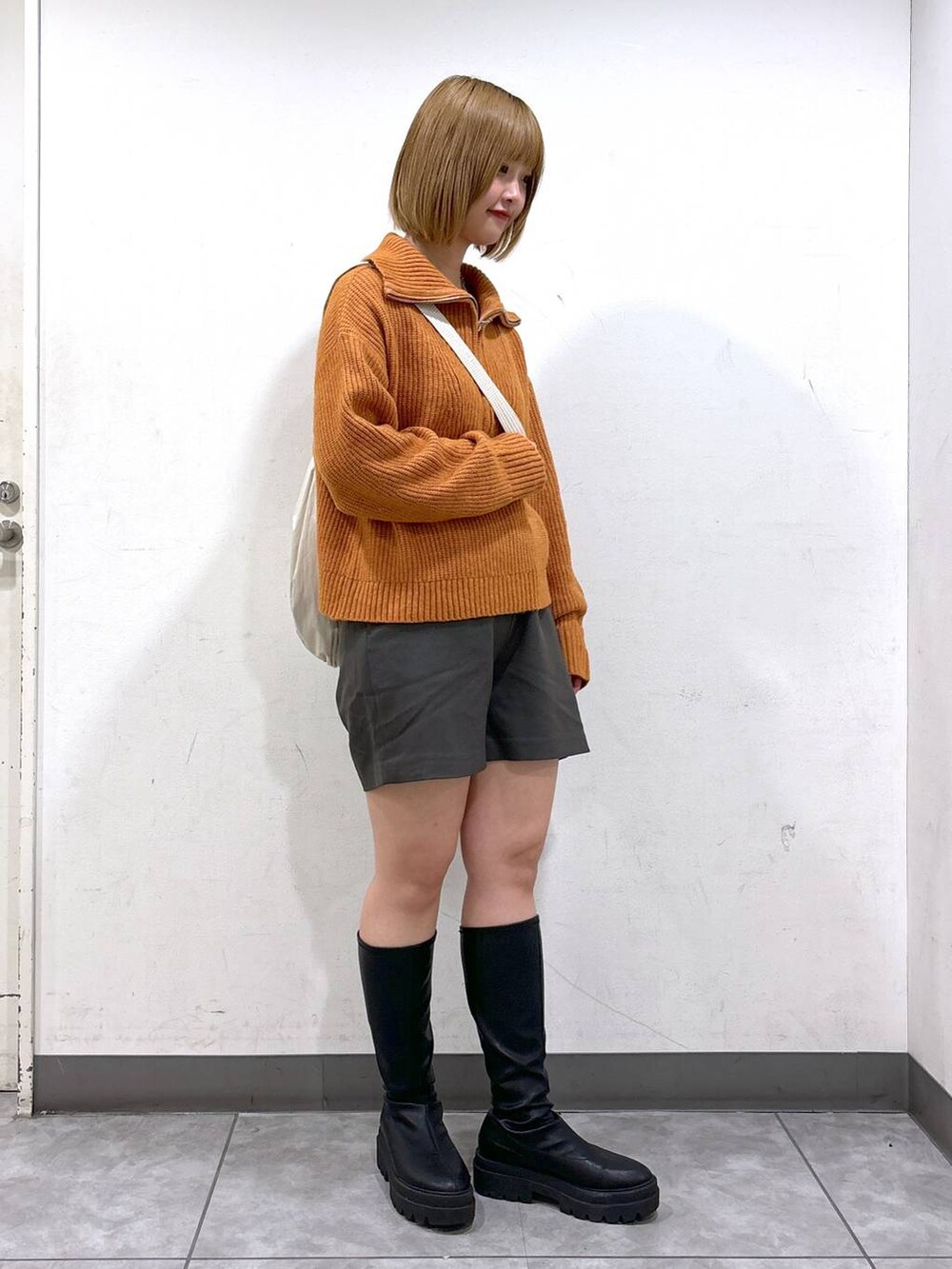 ブラック系のブーツ、グレー系のその他パンツ、オレンジ系のニット/セーターを着用したレディースの秋コーディネートの2枚目の写真