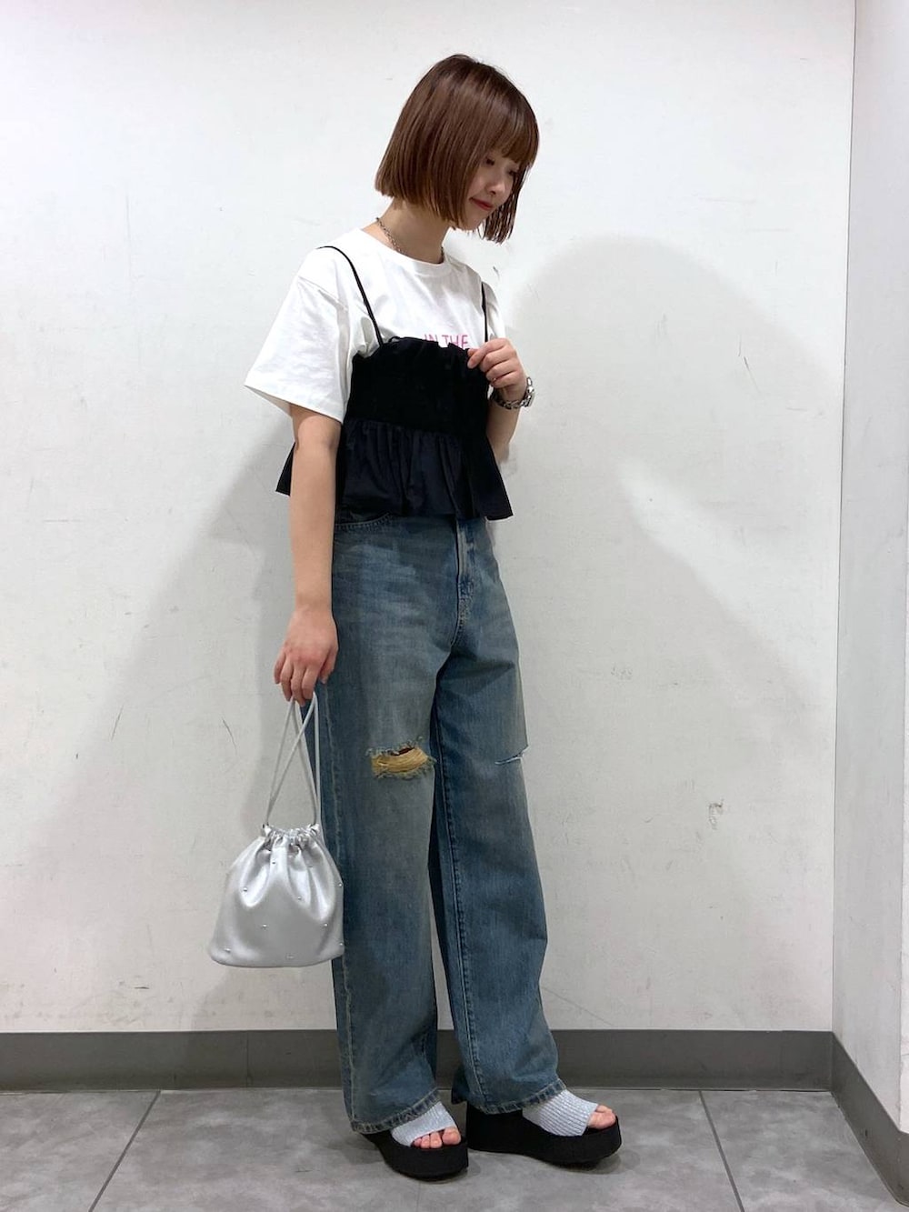 シルバー系のサンダル、シルバー系のショルダーバッグ、ブルー系のデニムパンツを着用したレディースの夏コーディネートの2枚目の写真