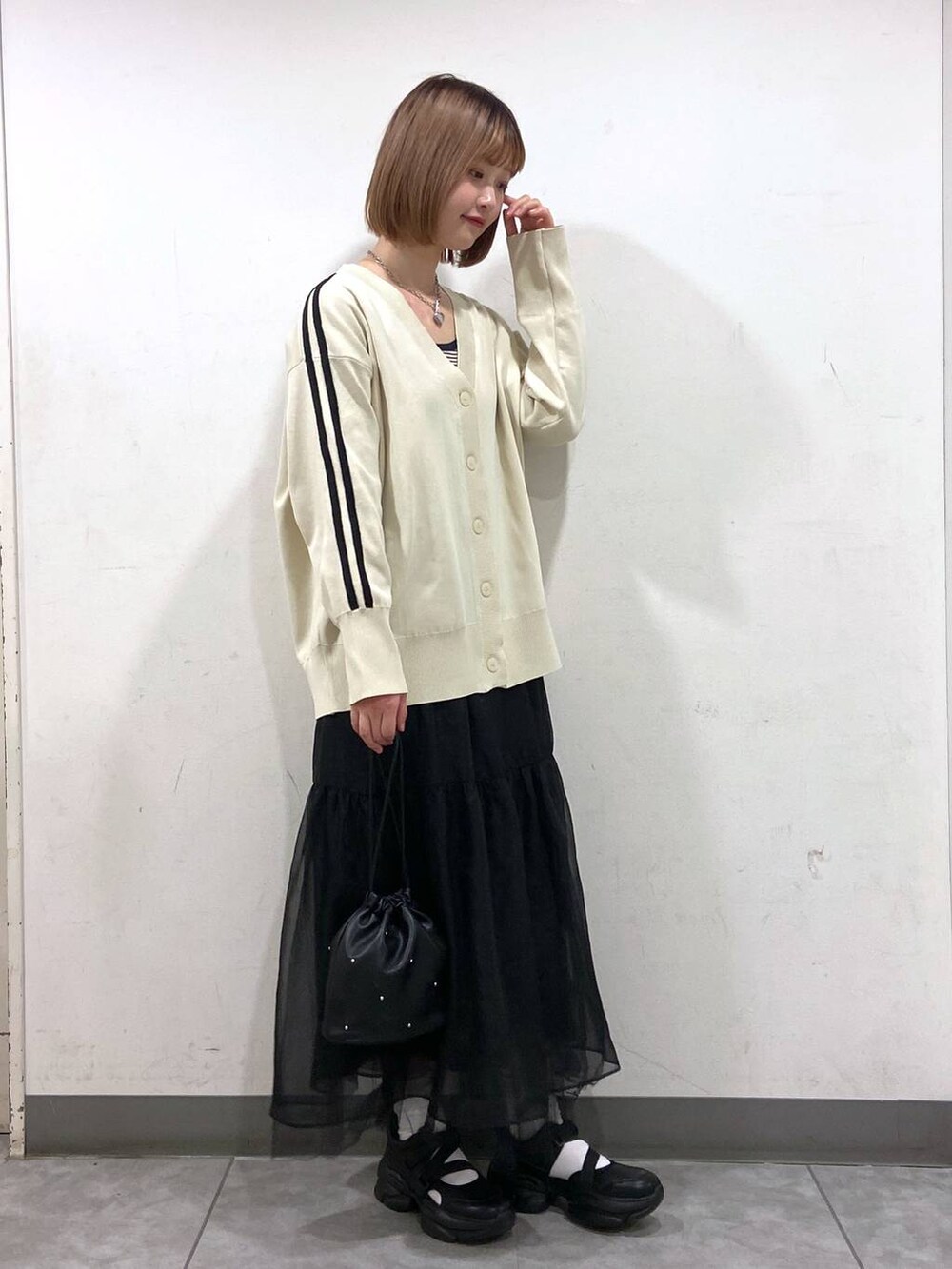 ブラック系のサンダル、ブラック系のショルダーバッグ、ホワイト系のカーディガン/ボレロを着用したレディースの春コーディネートの2枚目の写真