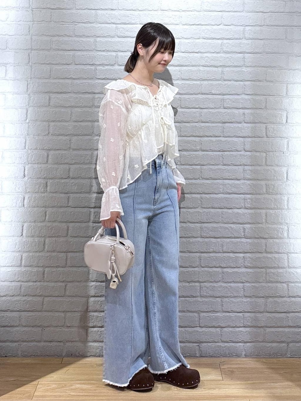 ホワイト系のボストンバッグ、ブルー系のデニムパンツ、ブラウン系のサンダルを着用したレディースの春コーディネートの2枚目の写真