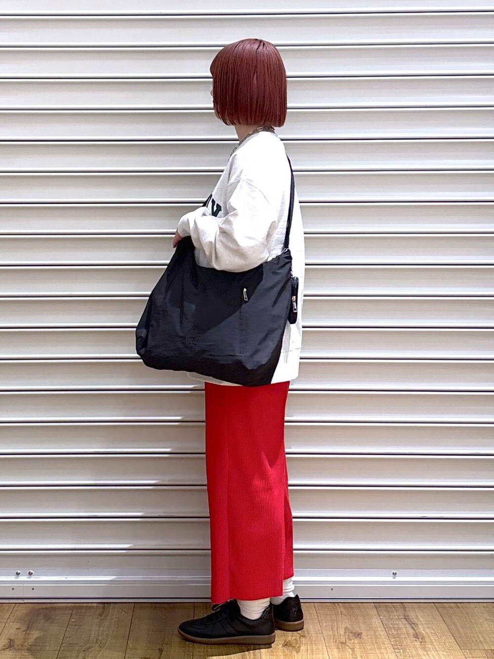 レッド系のスカート、グレー系のスウェット、ブラック系のショルダーバッグを着用したレディースの春コーディネートの3枚目の写真