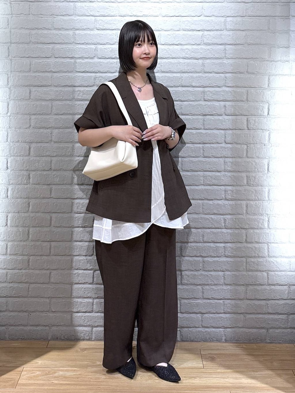 ブラック系のパンプス、ブラウン系のテーラードジャケット、ブラウン系のスラックスを着用したレディースの夏コーディネートの2枚目の写真