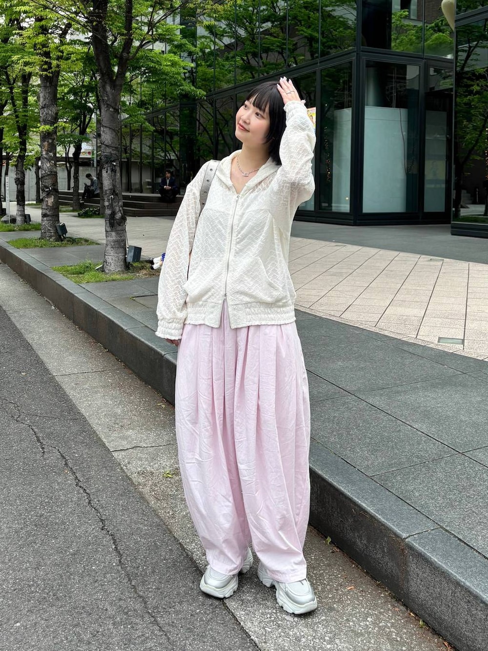 ホワイト系のパーカー、ピンク系のカーゴパンツ、シルバー系のスニーカーを着用したレディースの春コーディネートの4枚目の写真