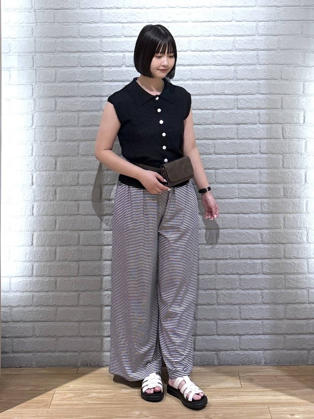 ブラック系のベスト、ホワイト系のその他パンツ、ホワイト系のサンダルを着用したレディースの夏コーディネートの2枚目の写真