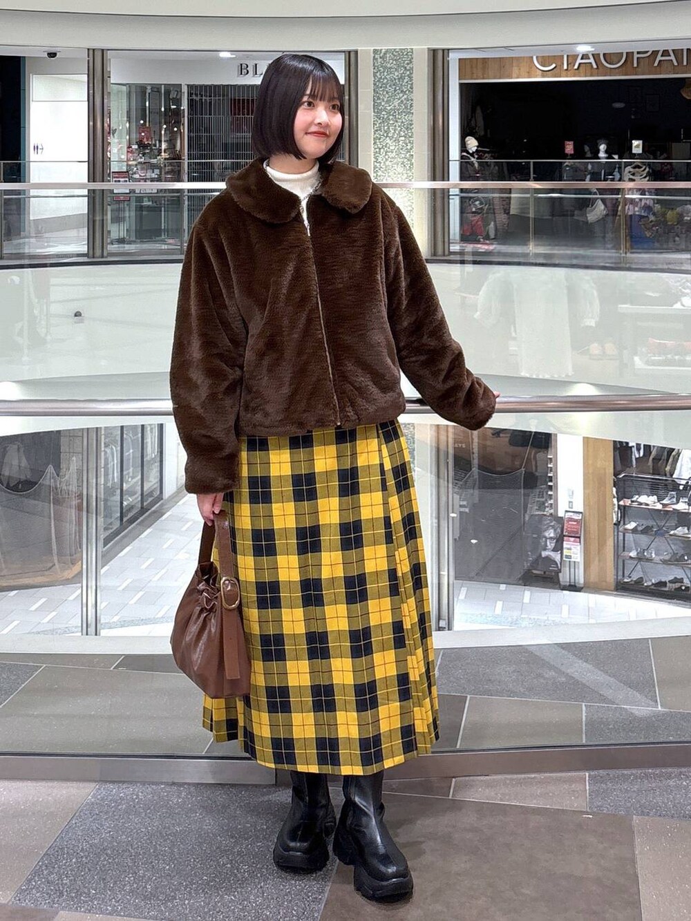 ブラック系のブーツ、ホワイト系のニット/セーター、ブラウン系のブルゾンを着用したレディースの冬コーディネートの2枚目の写真