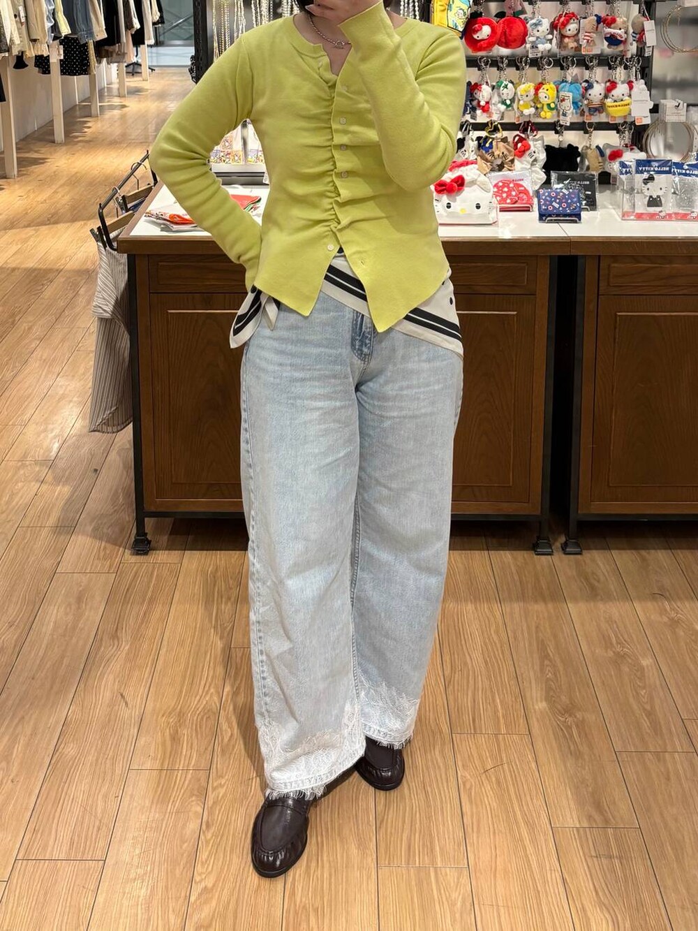 ブルー系のデニムパンツ、ブラウン系のローファー、イエロー系のカーディガン/ボレロを着用したレディースの春コーディネートの3枚目の写真