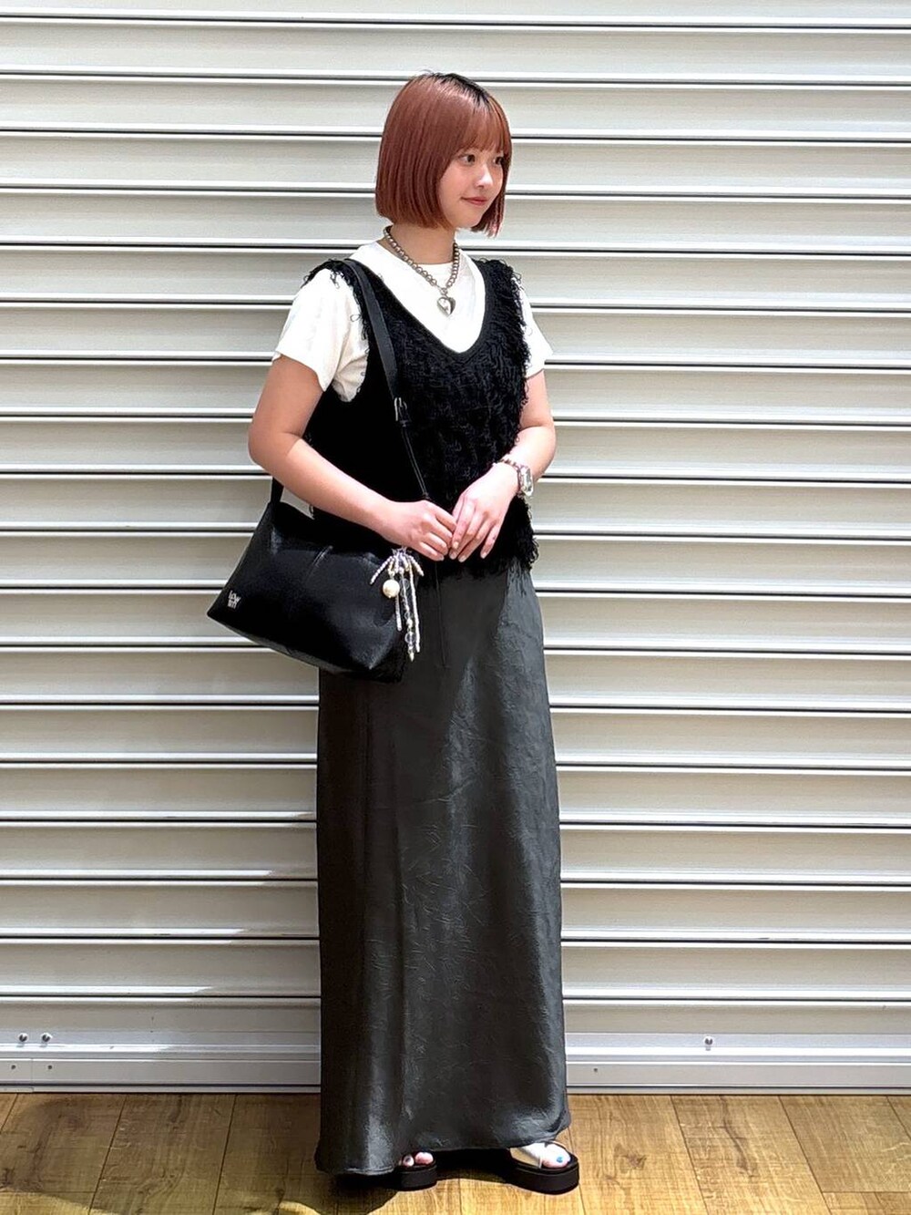 シルバー系のサンダル、グレー系のスカート、ブラック系のショルダーバッグを着用したレディースの夏コーディネートの2枚目の写真