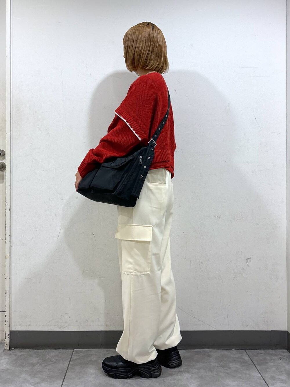 ホワイト系のニット/セーター、ブラック系のブーツ、ホワイト系のショルダーバッグを着用したレディースの秋コーディネートの3枚目の写真