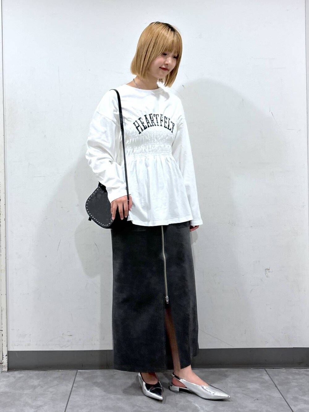 シルバー系のパンプス、ブラック系のショルダーバッグ、グレー系のスカートを着用したレディースの秋コーディネートの2枚目の写真