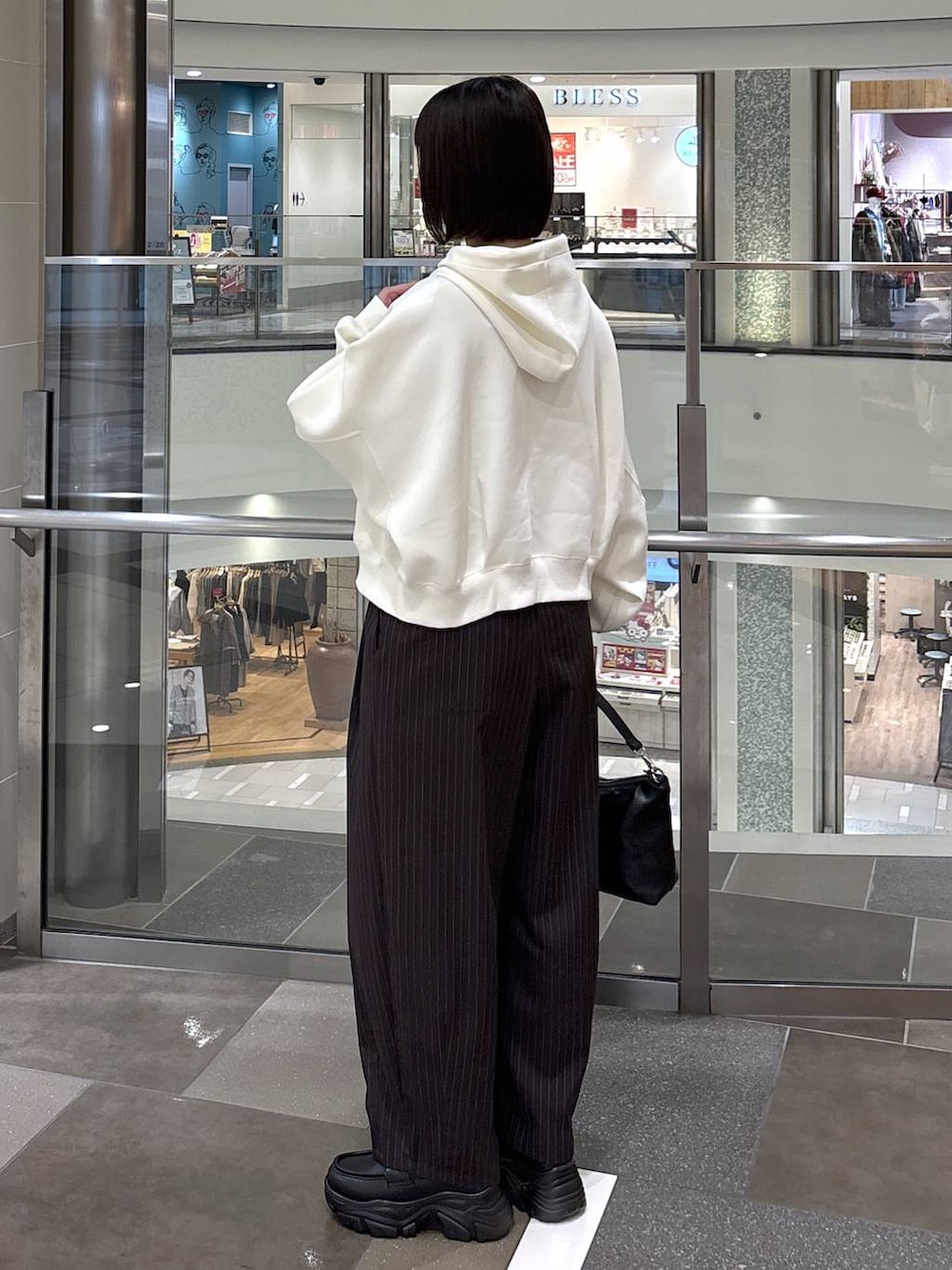 ブラウン系のその他パンツ、ベージュ系のパーカー、ブラック系のショルダーバッグを着用したレディースの冬コーディネートの3枚目の写真