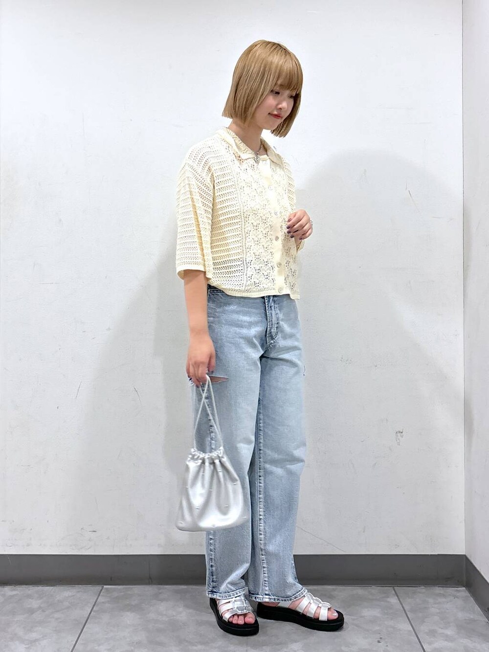 シルバー系のショルダーバッグ、ホワイト系のニット/セーター、シルバー系のスニーカーを着用したレディースの夏コーディネートの2枚目の写真