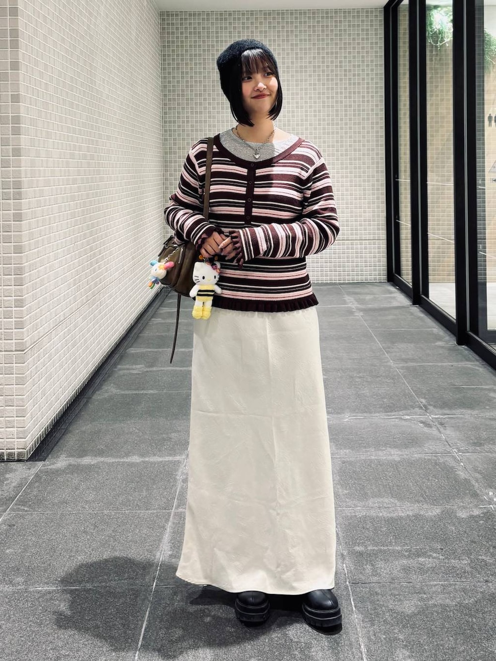 ホワイト系のスカート、ブラック系のブーツ、ブラウン系のニット/セーターを着用したレディースの冬コーディネートの3枚目の写真