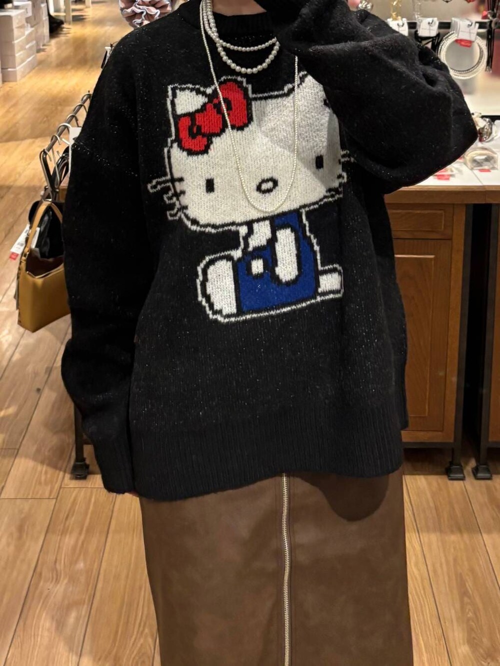 ブラウン系のスカート、ブラック系のニット/セーター、ホワイト系のネックレスを着用したレディースの秋コーディネートの2枚目の写真