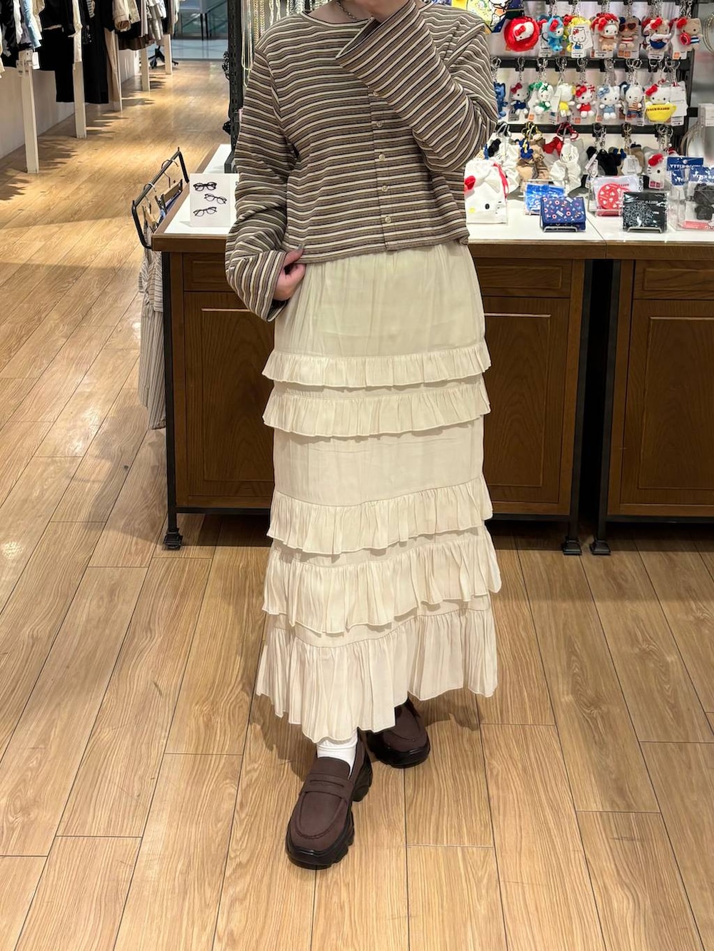 ブラウン系のローファー、ホワイト系のスカート、ベージュ系のカーディガン/ボレロを着用したレディースの春コーディネートの3枚目の写真