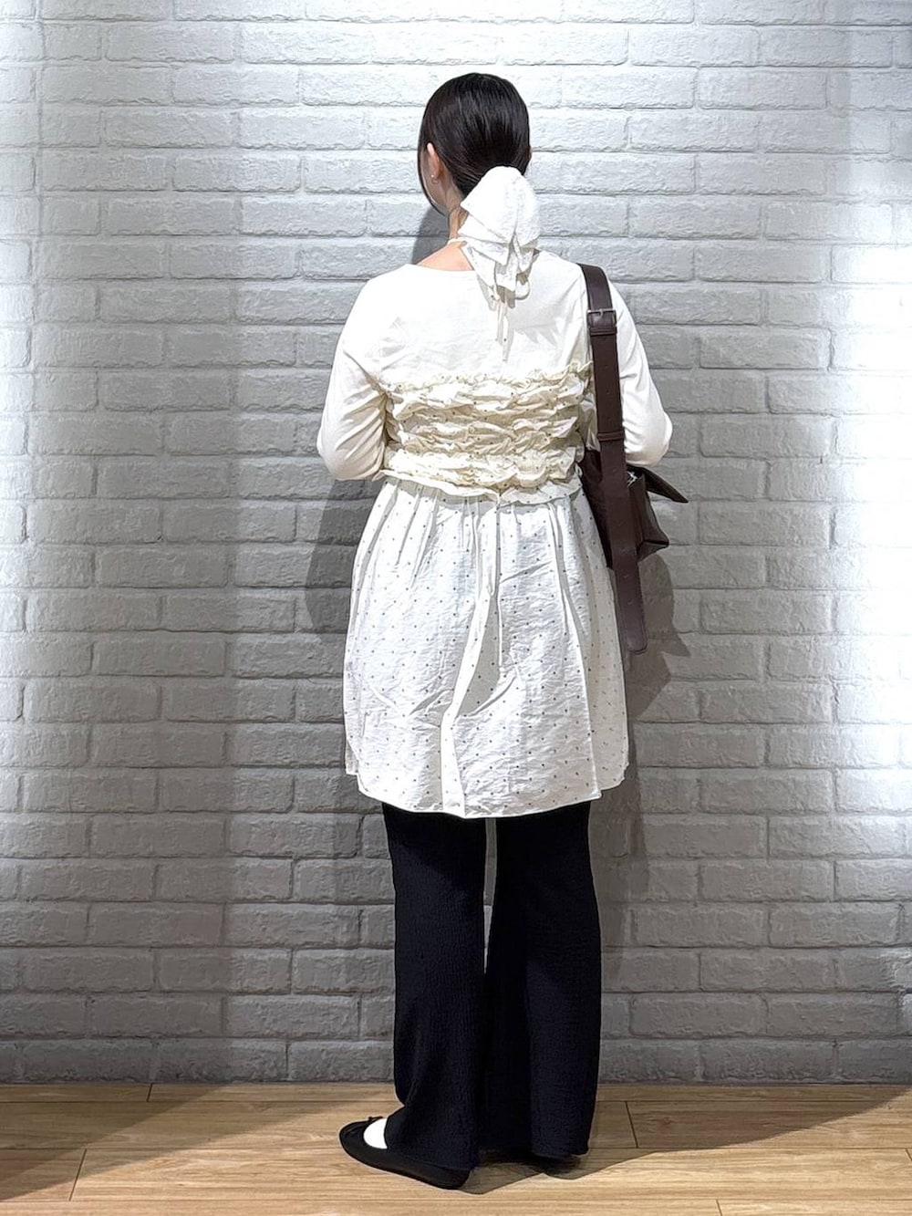 ブラウン系のショルダーバッグ、ブラック系のバレエシューズ、ホワイト系のTシャツ/カットソーを着用したレディースの秋コーディネートの3枚目の写真