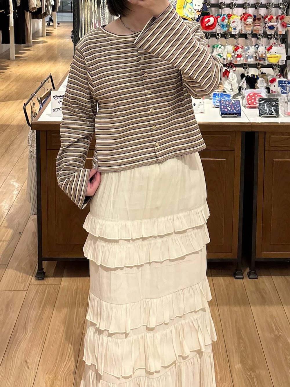 ブラウン系のローファー、ホワイト系のスカート、ベージュ系のカーディガン/ボレロを着用したレディースの春コーディネートの2枚目の写真