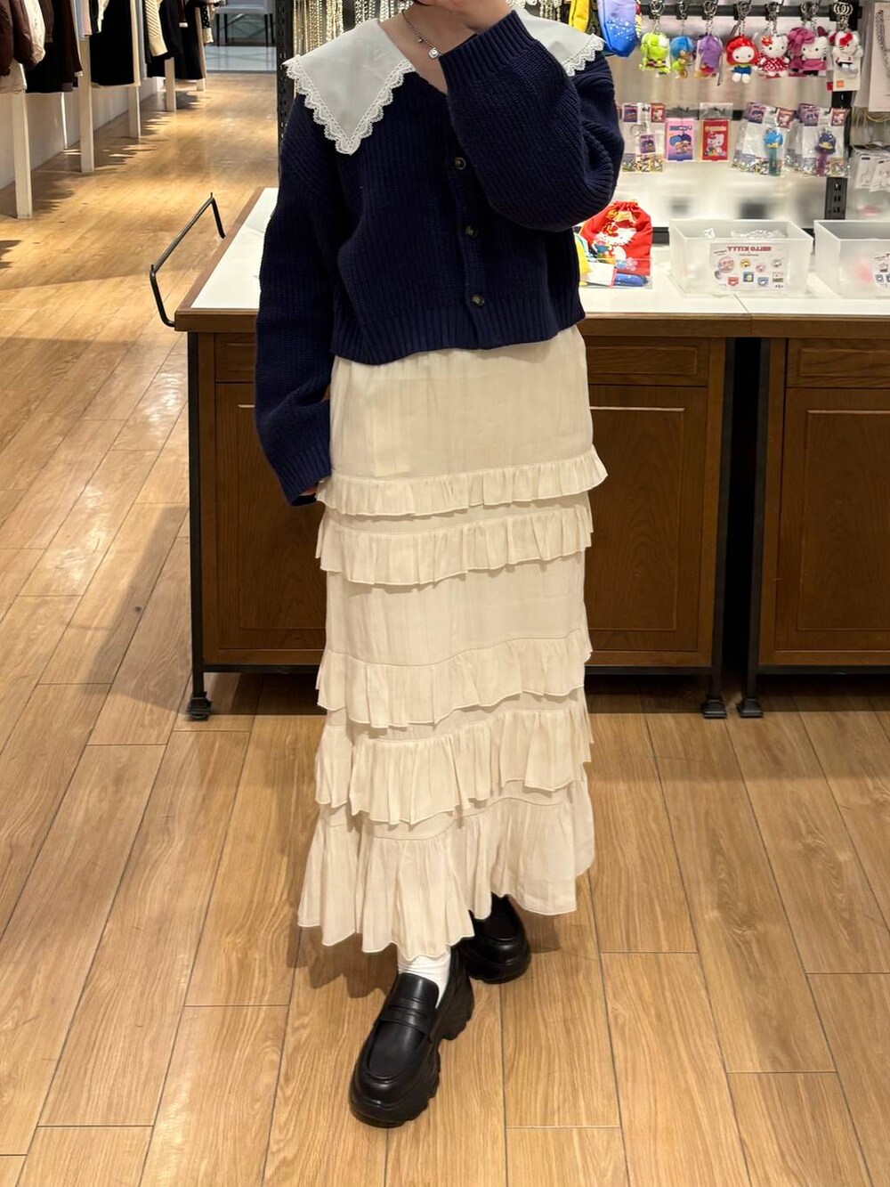 ブラック系のローファー、ホワイト系のスカート、ブルー系のカーディガン/ボレロを着用したレディースの冬コーディネートの3枚目の写真