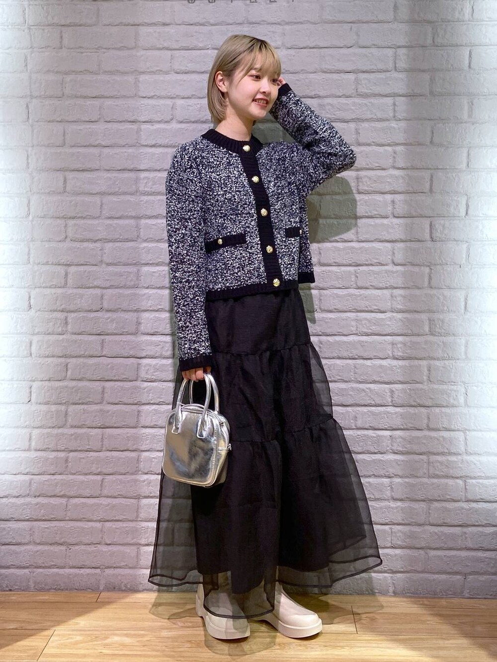 ホワイト系のブーツ、ブラック系のカーディガン/ボレロ、ブラック系のスカートを着用したレディースの秋コーディネートの2枚目の写真