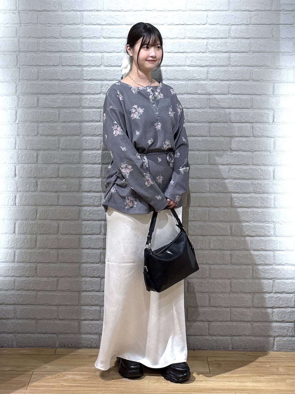 ブラック系のハンドバッグ、グレー系のTシャツ/カットソー、ホワイト系のスカートを着用したレディースの秋コーディネートの2枚目の写真
