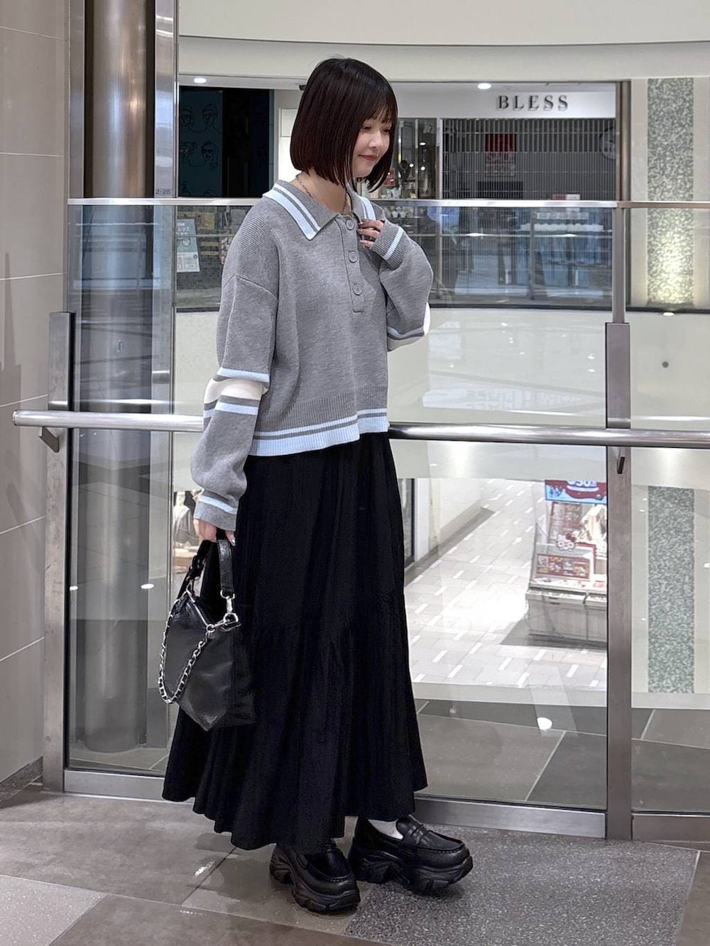 ブラック系のショルダーバッグ、ブラック系のローファー、ブラック系のスカートを着用したレディースの冬コーディネートの2枚目の写真