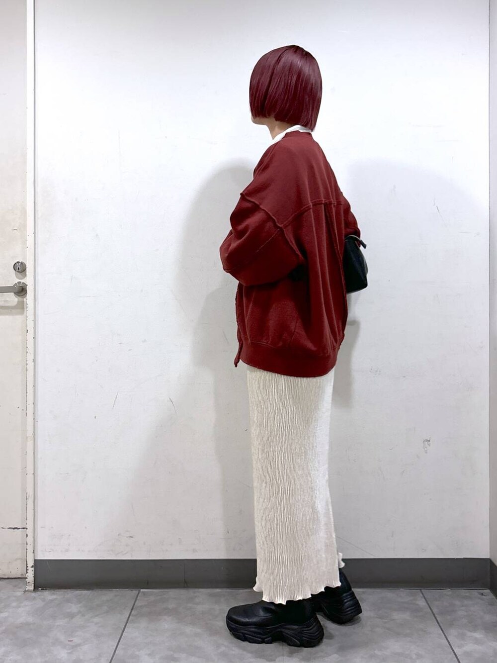 ブラック系のブーツ、ホワイト系のスカート、シルバー系のショルダーバッグを着用したレディースの秋コーディネートの3枚目の写真