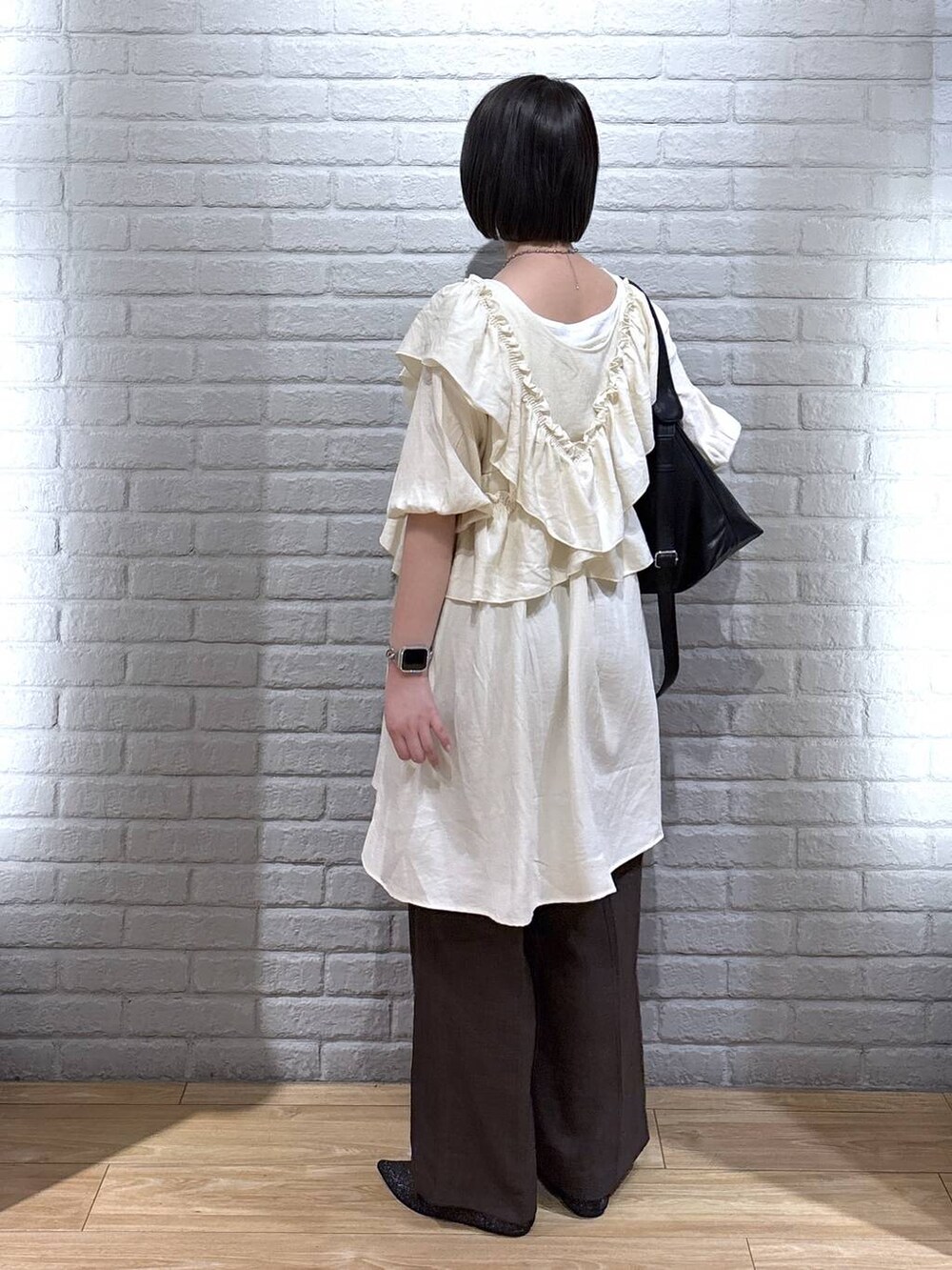 ブラック系のパンプス、ブラウン系のスラックス、ブラック系のショルダーバッグを着用したレディースの夏コーディネートの3枚目の写真