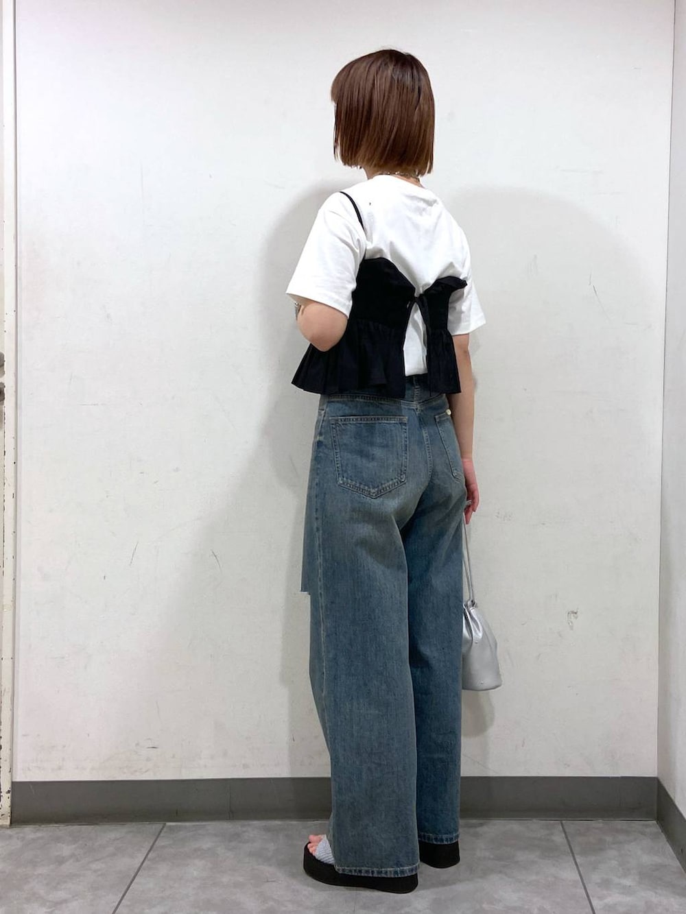 シルバー系のサンダル、シルバー系のショルダーバッグ、ブルー系のデニムパンツを着用したレディースの夏コーディネートの3枚目の写真