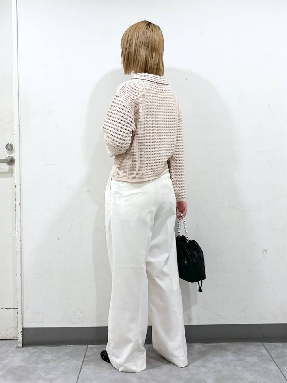 ホワイト系のスラックス、ブラック系のショルダーバッグ、ブラック系のバレエシューズを着用したレディースの秋コーディネートの3枚目の写真