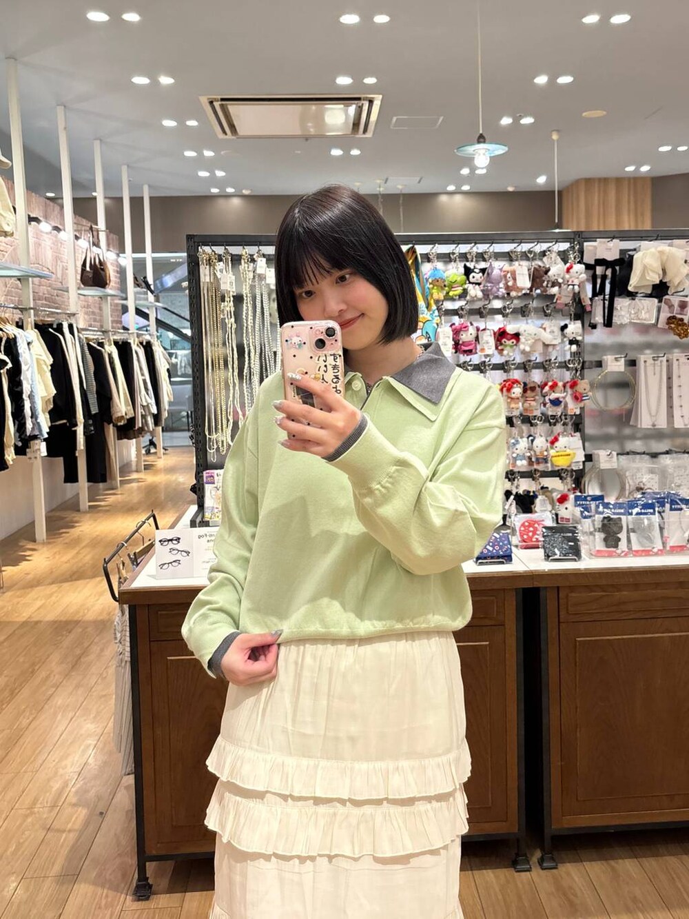 ブラウン系のローファー、ホワイト系のスカート、グリーン系のニット/セーターを着用したレディースの春コーディネートの3枚目の写真