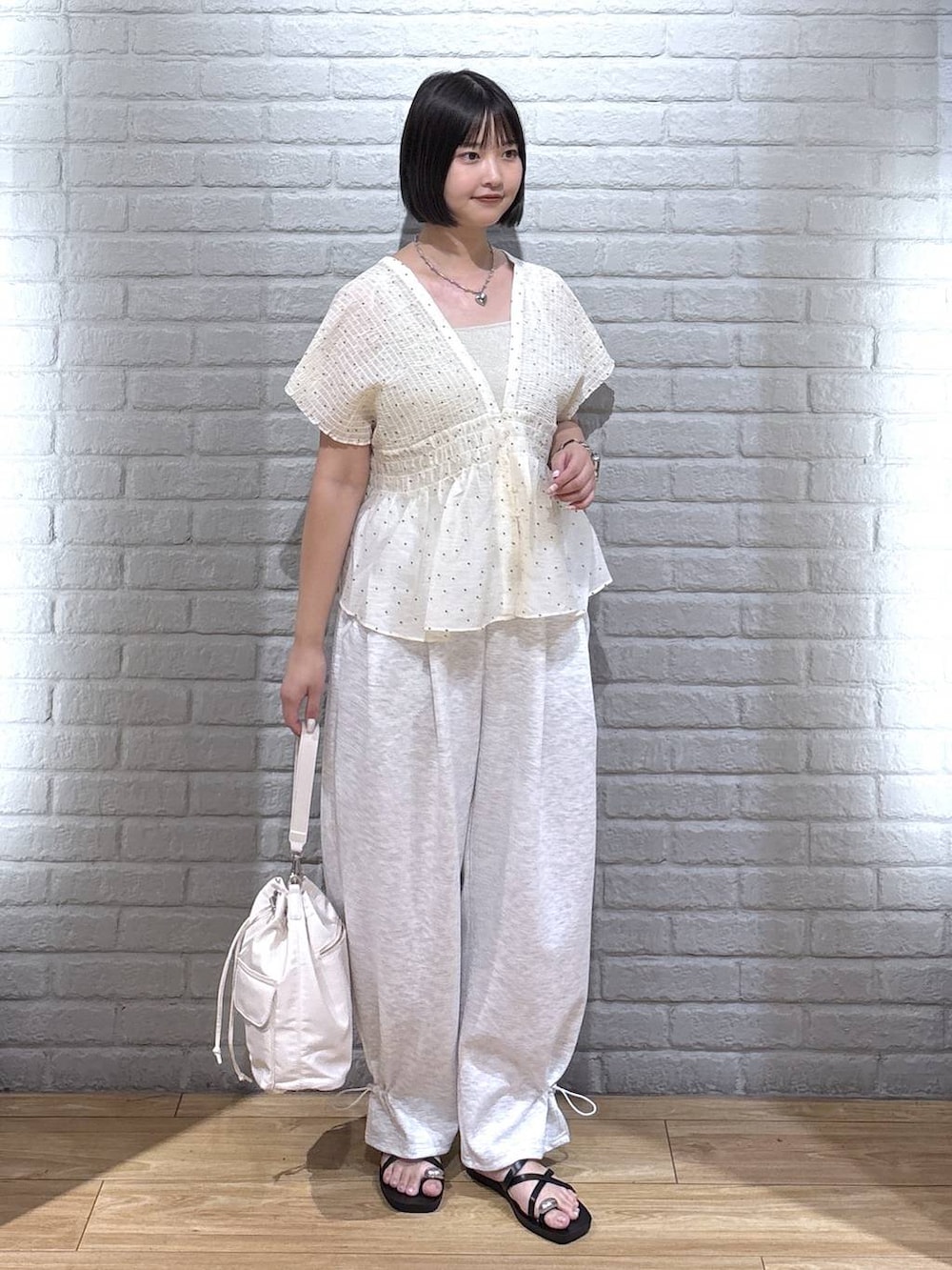 グレー系のスウェットパンツ、ゴールド系のタンクトップ、ブラック系のサンダルを着用したレディースの夏コーディネートの2枚目の写真