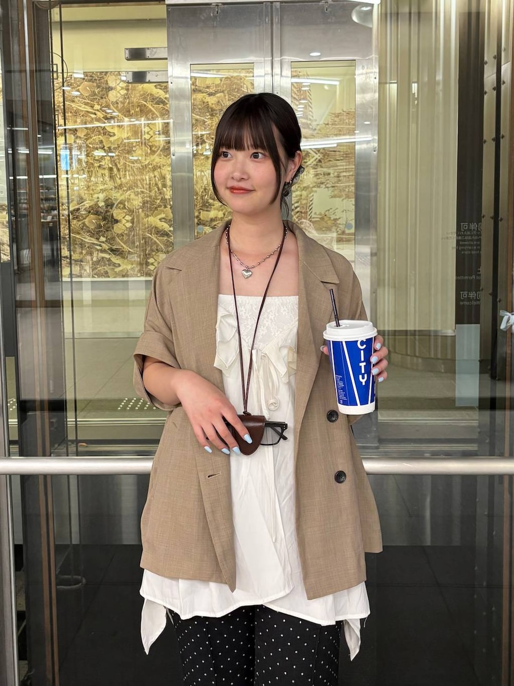 ベージュ系のテーラードジャケット、ホワイト系のチュニックを着用したレディースの夏コーディネートの2枚目の写真
