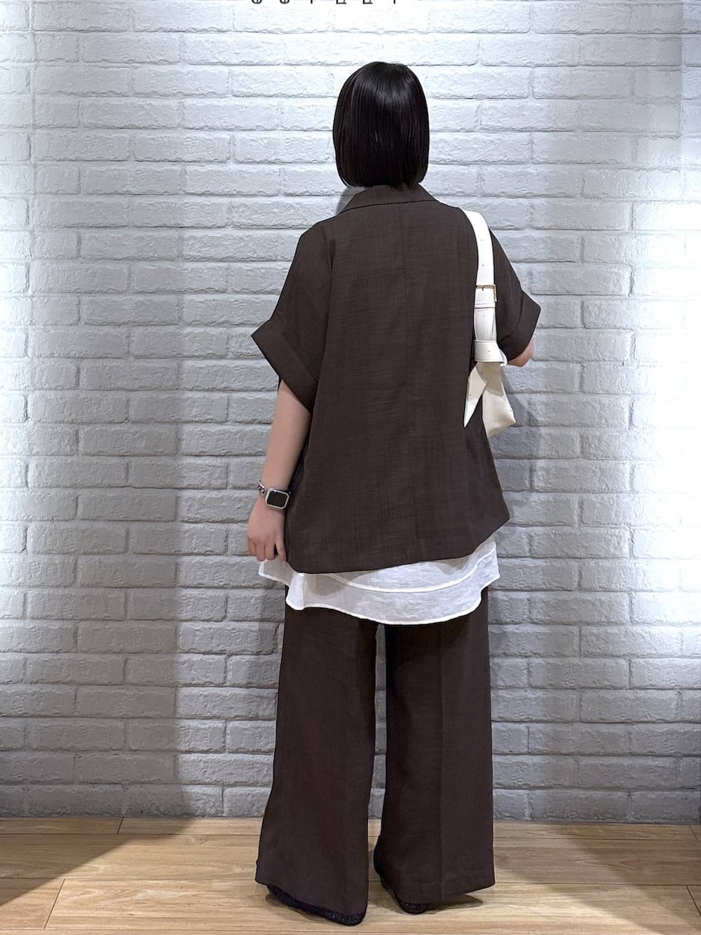 ブラック系のパンプス、ブラウン系のテーラードジャケット、ブラウン系のスラックスを着用したレディースの夏コーディネートの3枚目の写真