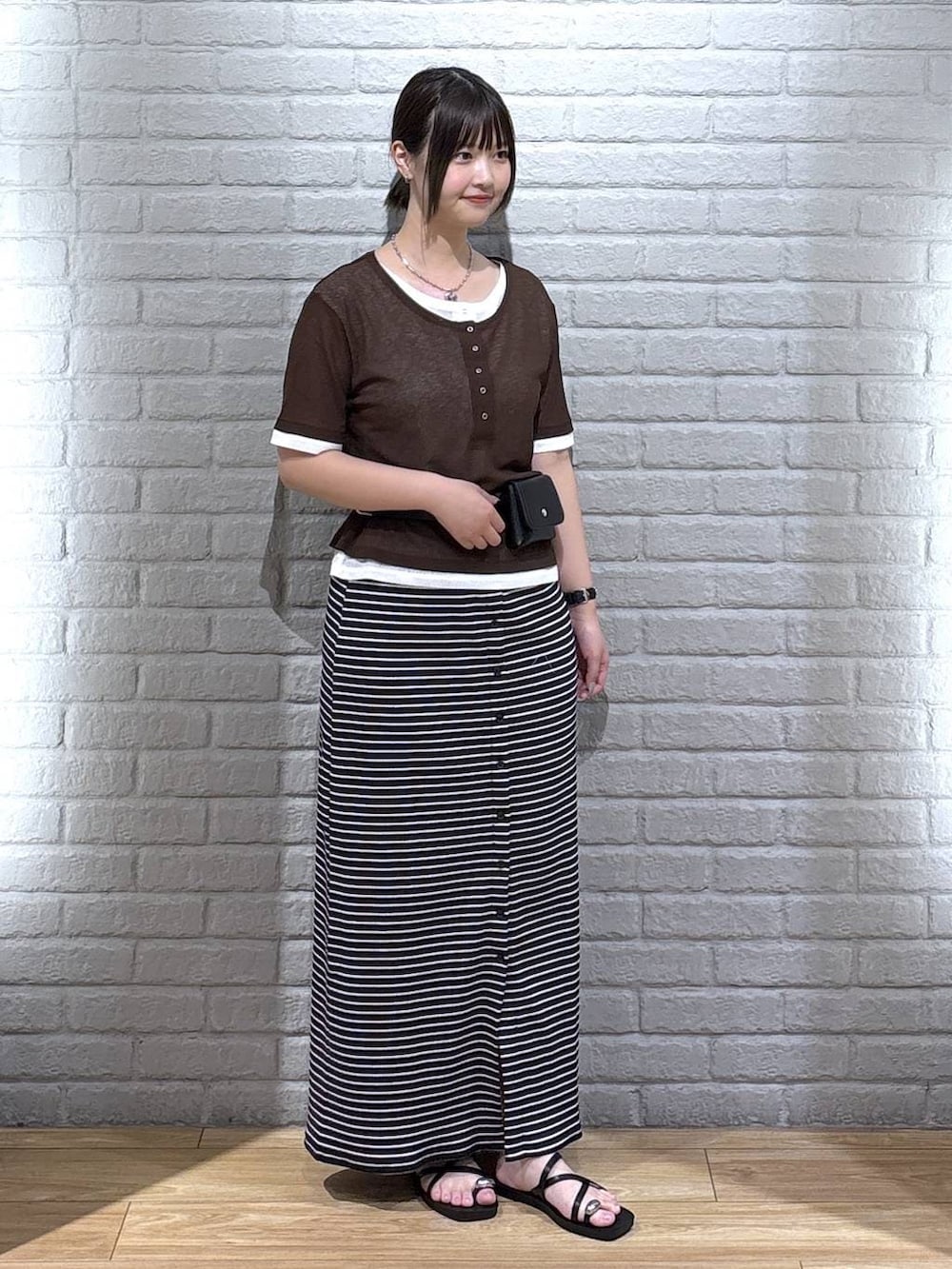 ブラック系のサンダル、ブラウン系のTシャツ/カットソー、ブラック系のスカートを着用したレディースの夏コーディネートの2枚目の写真