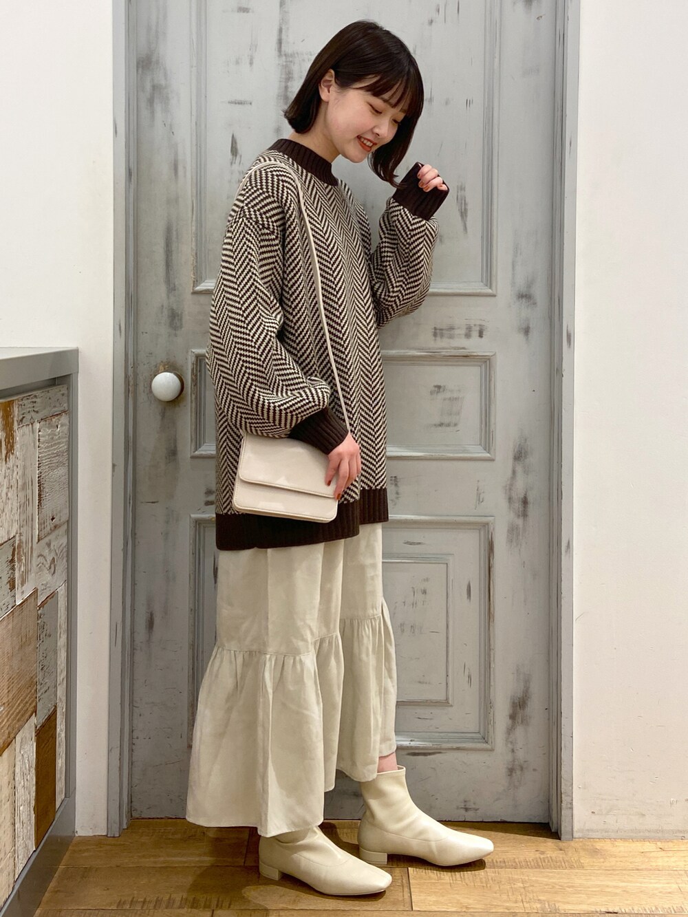 ブラウン系のワンピース、ホワイト系のショルダーバッグ、ホワイト系のブーツを着用したレディースの冬コーディネートの2枚目の写真