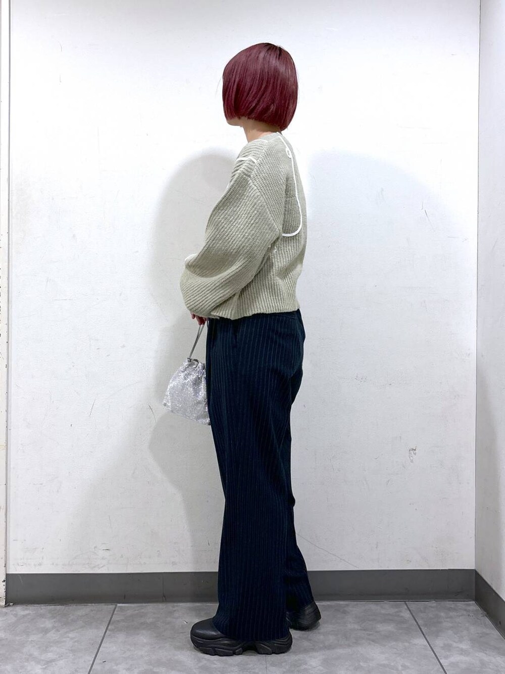 ブラック系のブーツ、シルバー系のショルダーバッグ、ブルー系のその他パンツを着用したレディースの秋コーディネートの3枚目の写真