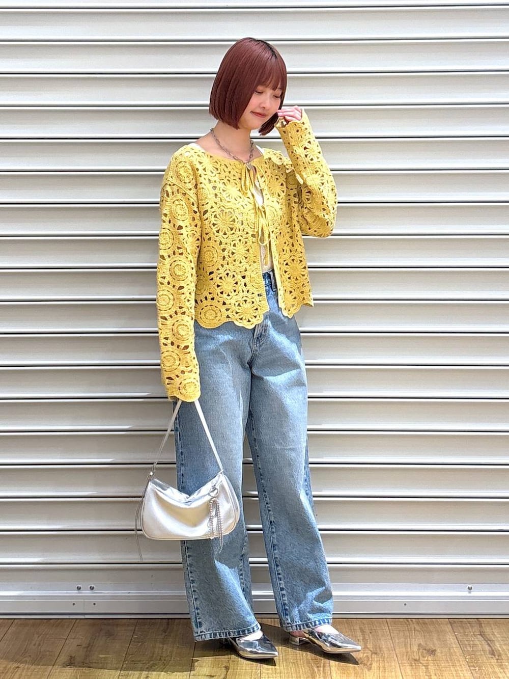 ブルー系のデニムパンツ、ゴールド系のタンクトップ、シルバー系のトートバッグを着用したレディースの春コーディネートの2枚目の写真