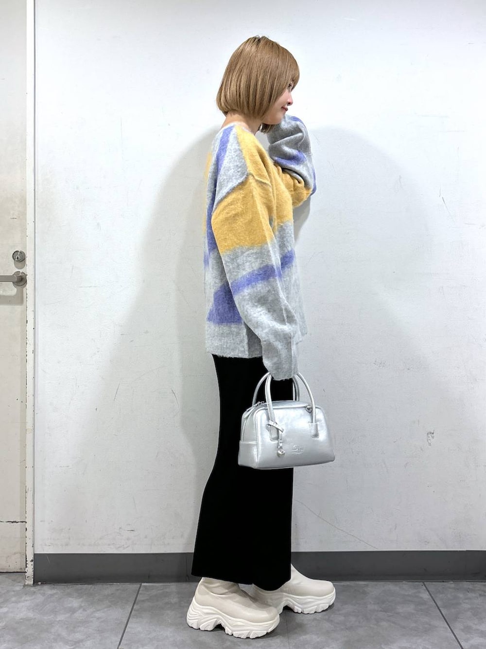 ブラック系のスカート、シルバー系のボストンバッグ、ホワイト系のブーツを着用したレディースの秋コーディネートの2枚目の写真