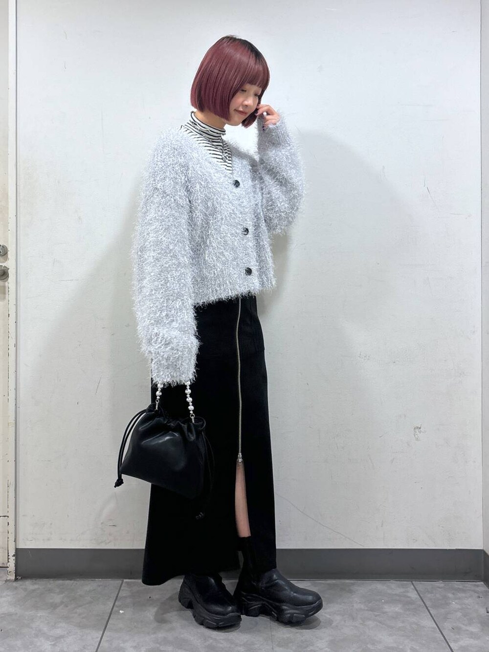 ブラック系のブーツ、ブラック系のスカート、ブラック系のショルダーバッグを着用したレディースの冬コーディネートの2枚目の写真