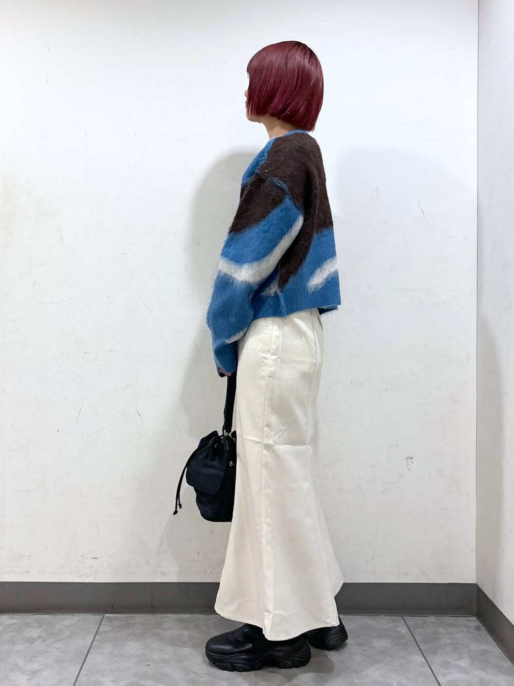 ホワイト系のスカート、ブラック系のショルダーバッグ、ブルー系のニット/セーターを着用したレディースの秋コーディネートの3枚目の写真