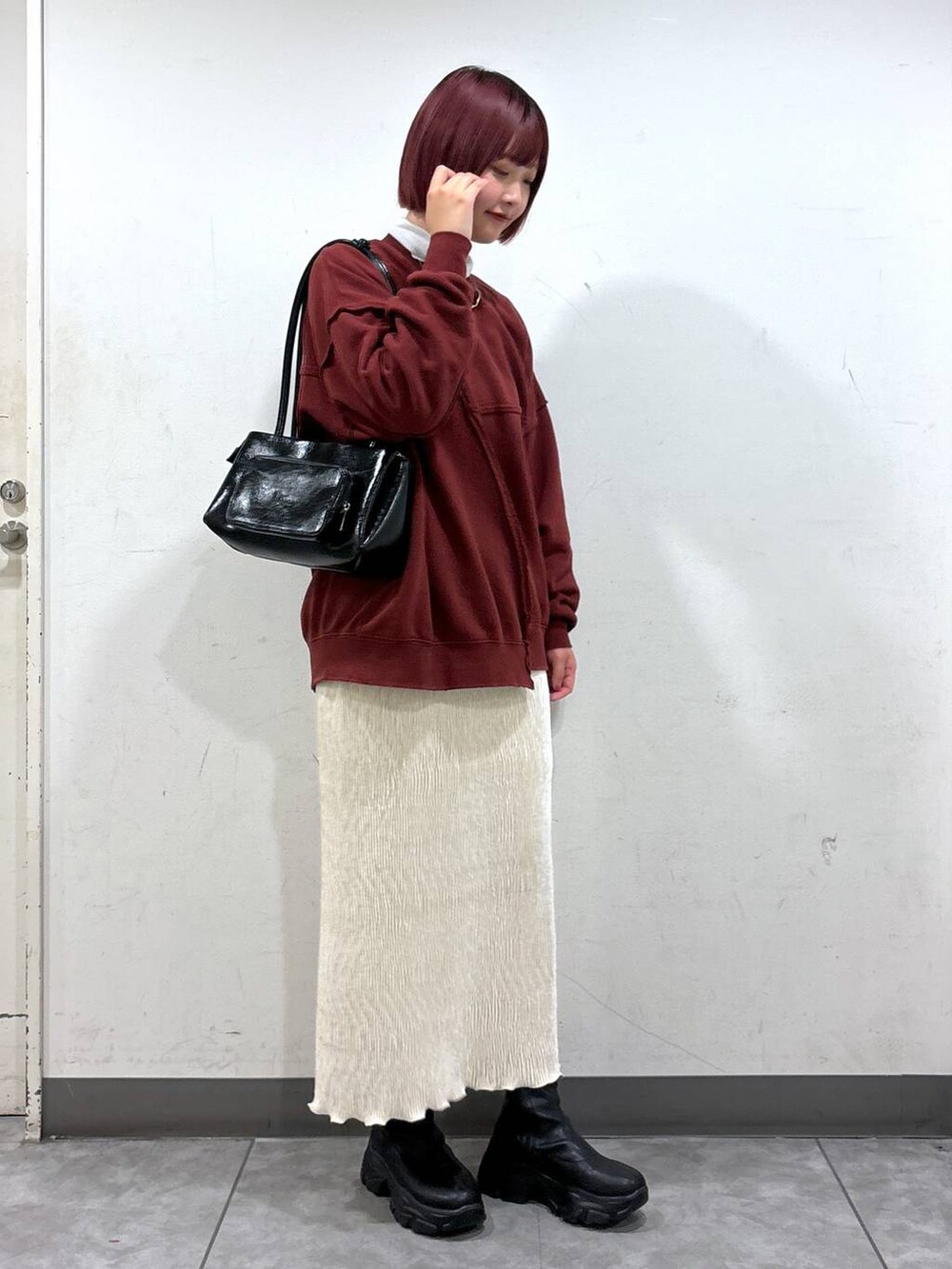 ブラック系のブーツ、ホワイト系のスカート、シルバー系のショルダーバッグを着用したレディースの秋コーディネートの2枚目の写真