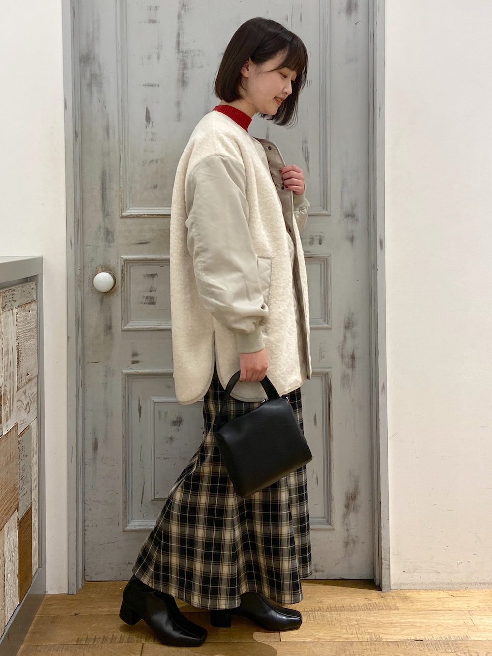 ホワイト系のブルゾン、レッド系のニット/セーター、ブラック系のスカートを着用したレディースの冬コーディネートの2枚目の写真