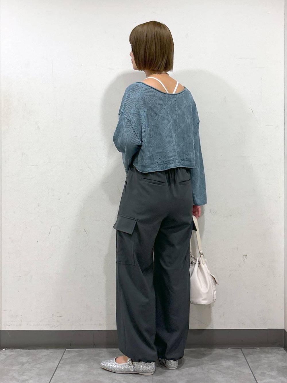 ブルー系のニット/セーター、ホワイト系のショルダーバッグ、グレー系のスラックスを着用したレディースの秋コーディネートの3枚目の写真