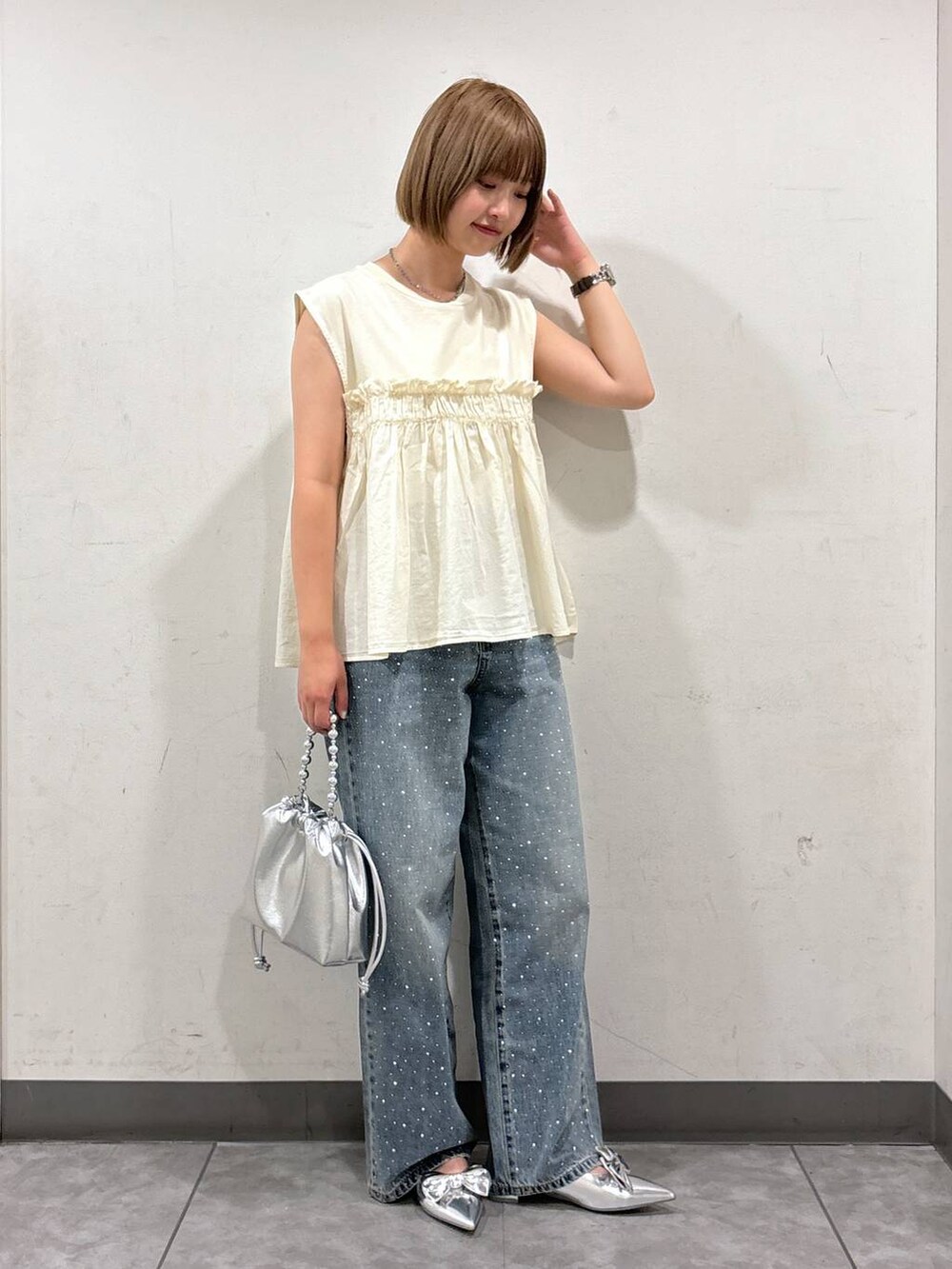 シルバー系のパンプス、シルバー系のショルダーバッグ、ブルー系のデニムパンツを着用したレディースの夏コーディネートの2枚目の写真