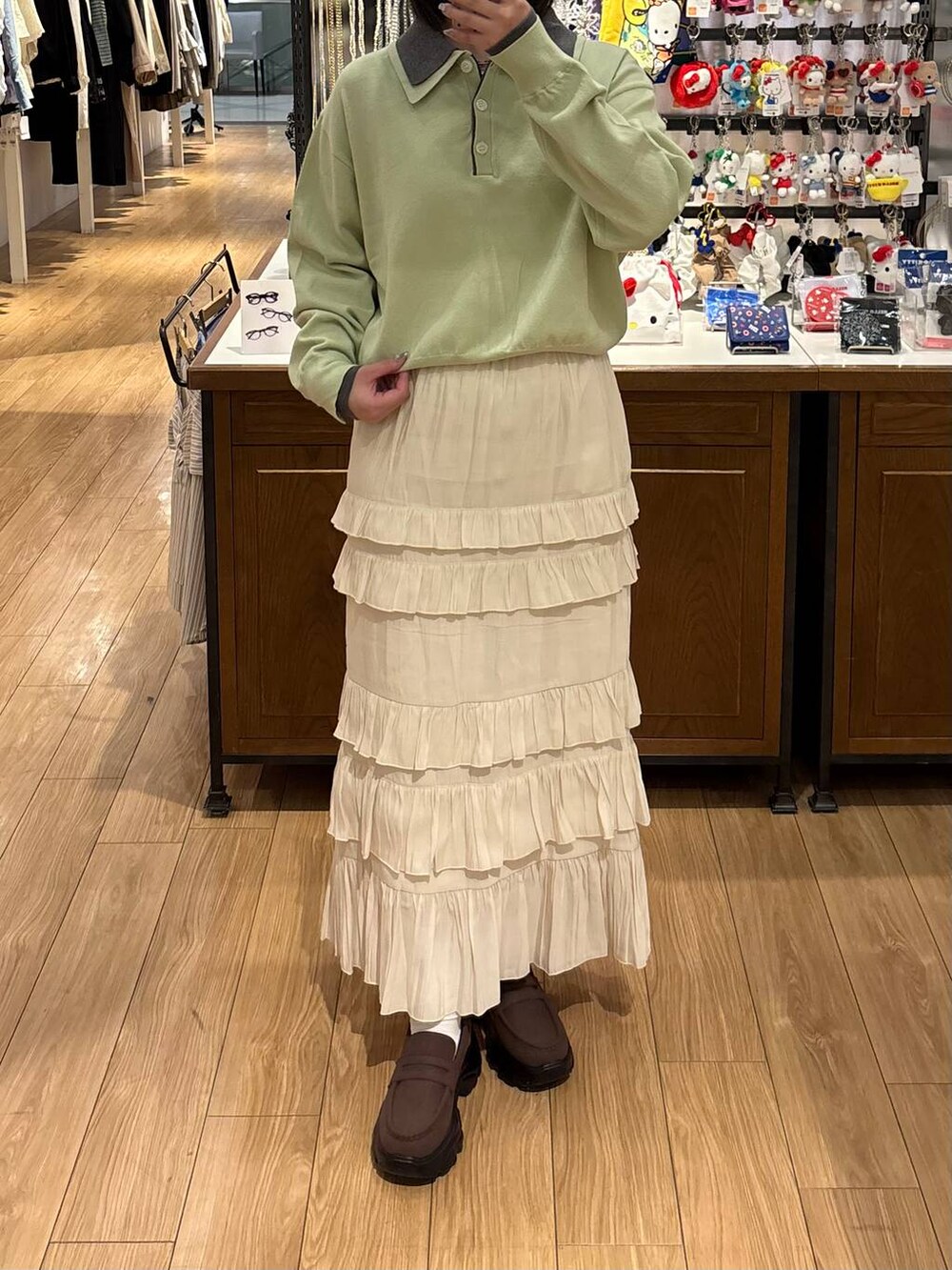 ブラウン系のローファー、ホワイト系のスカート、グリーン系のニット/セーターを着用したレディースの春コーディネートの2枚目の写真