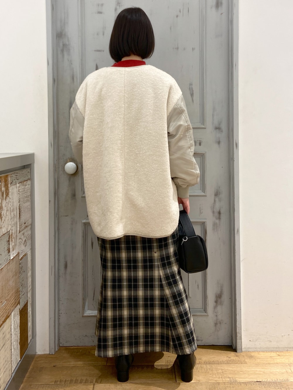 ホワイト系のブルゾン、レッド系のニット/セーター、ブラック系のスカートを着用したレディースの冬コーディネートの3枚目の写真