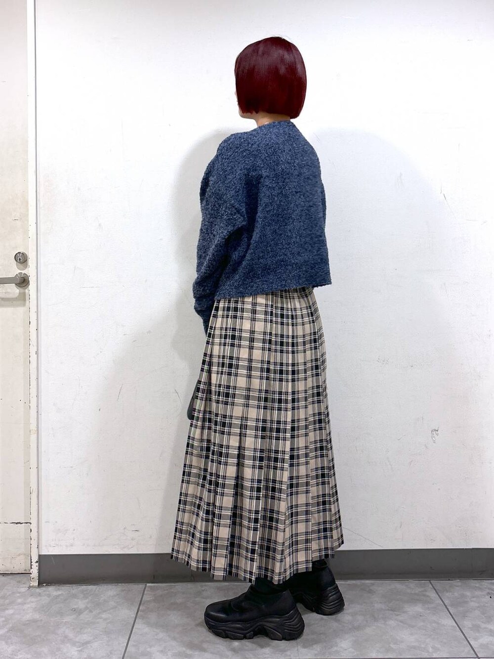 ブラック系のブーツ、ブラック系のボストンバッグ、ブルー系のニット/セーターを着用したレディースの秋コーディネートの3枚目の写真