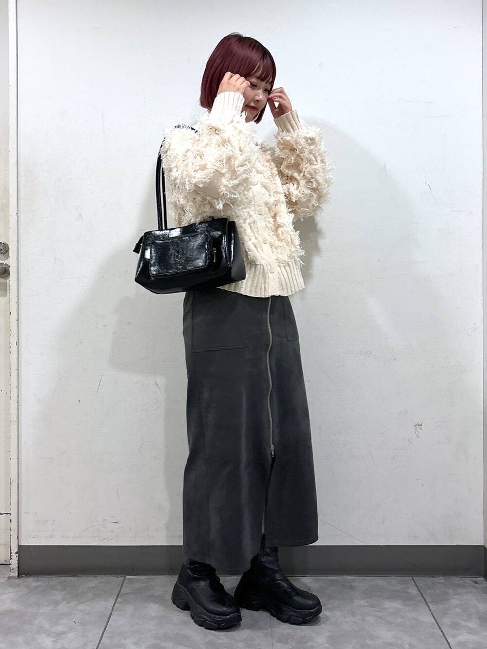 ブラック系のブーツ、ブラック系のショルダーバッグ、ブラック系のスカートを着用したレディースの冬コーディネートの2枚目の写真