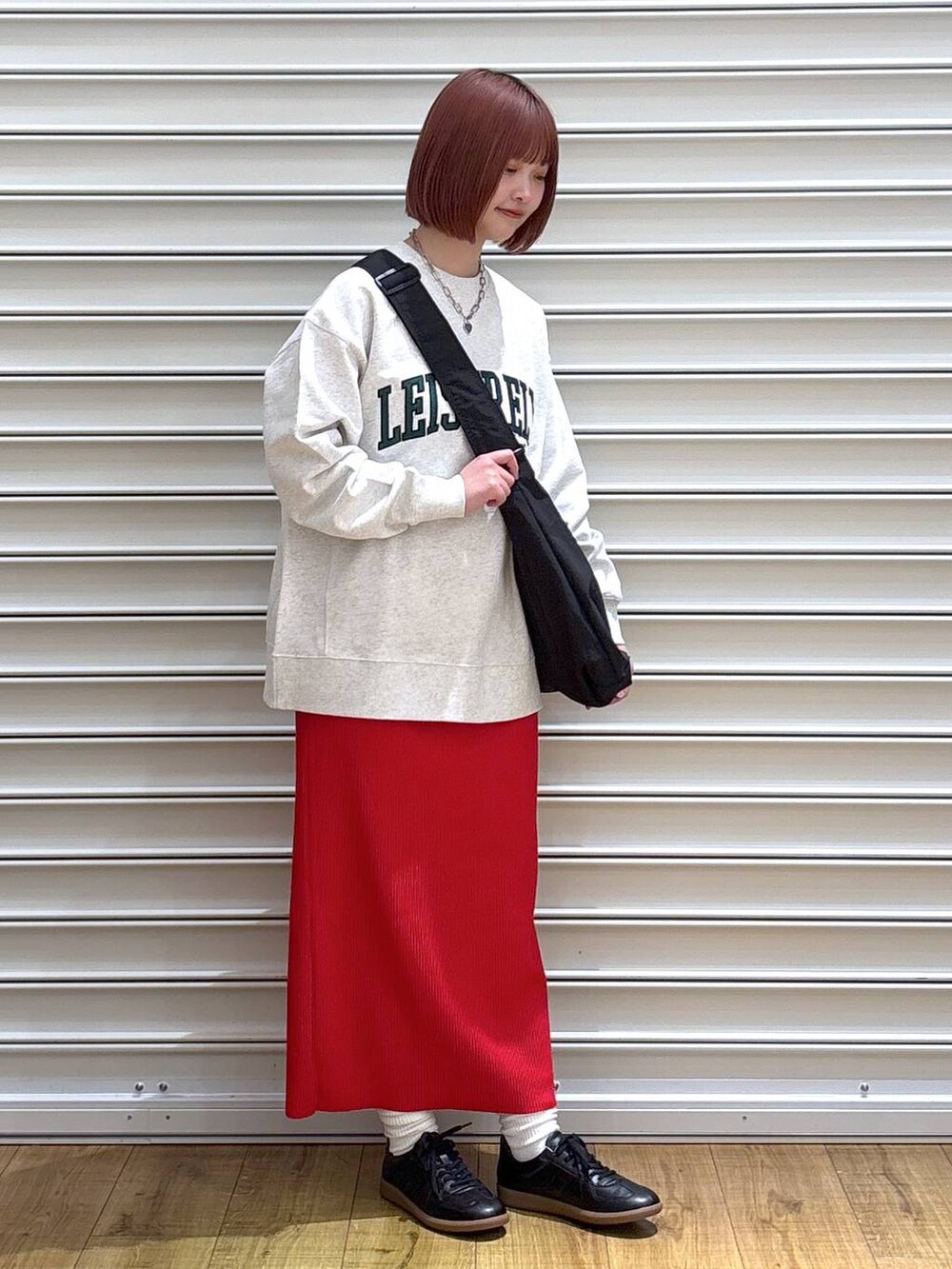 レッド系のスカート、グレー系のスウェット、ブラック系のショルダーバッグを着用したレディースの春コーディネートの2枚目の写真