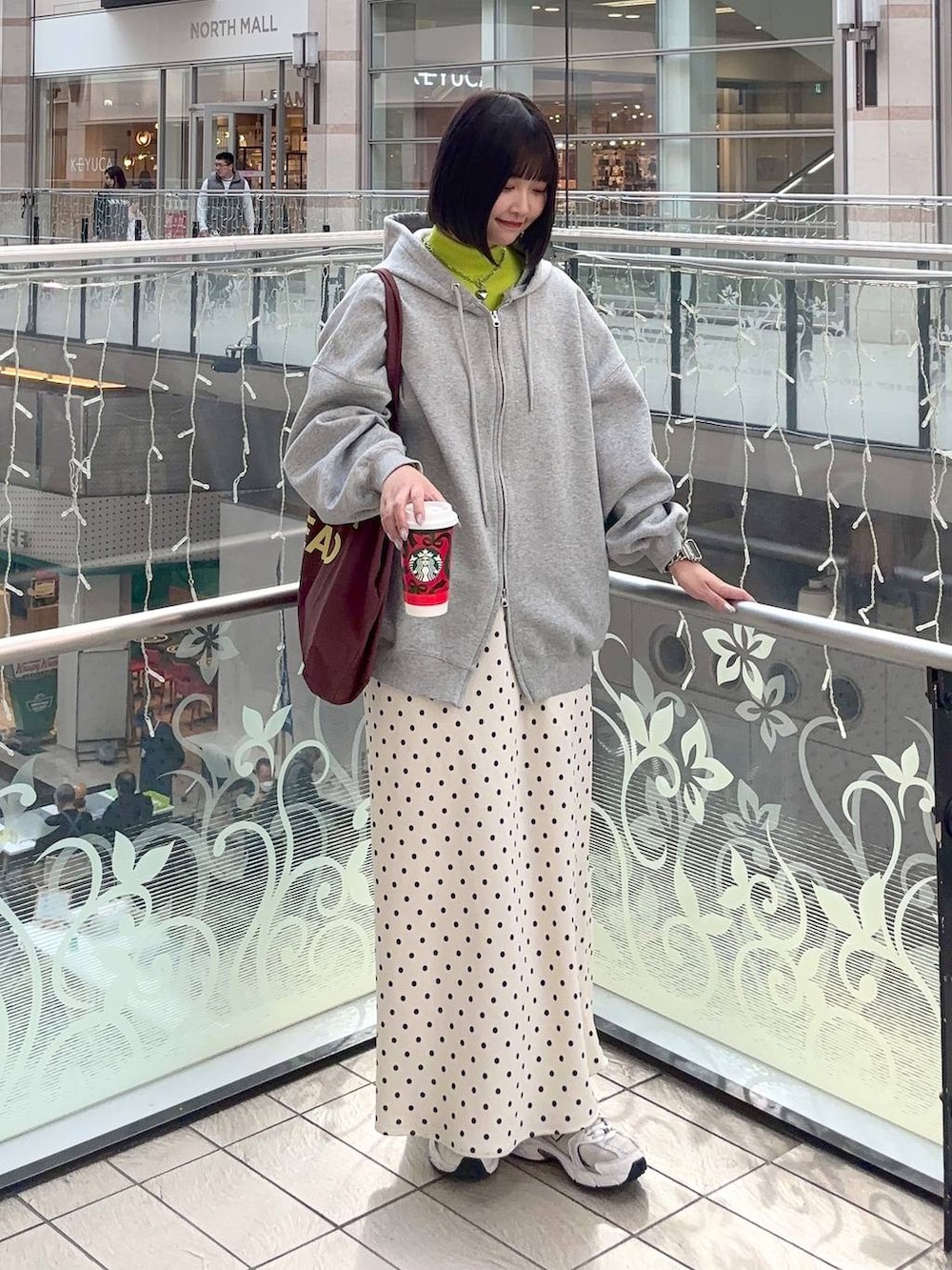 ホワイト系のスカート、イエロー系のニット/セーター、グレー系のパーカーを着用したレディースの冬コーディネートの2枚目の写真