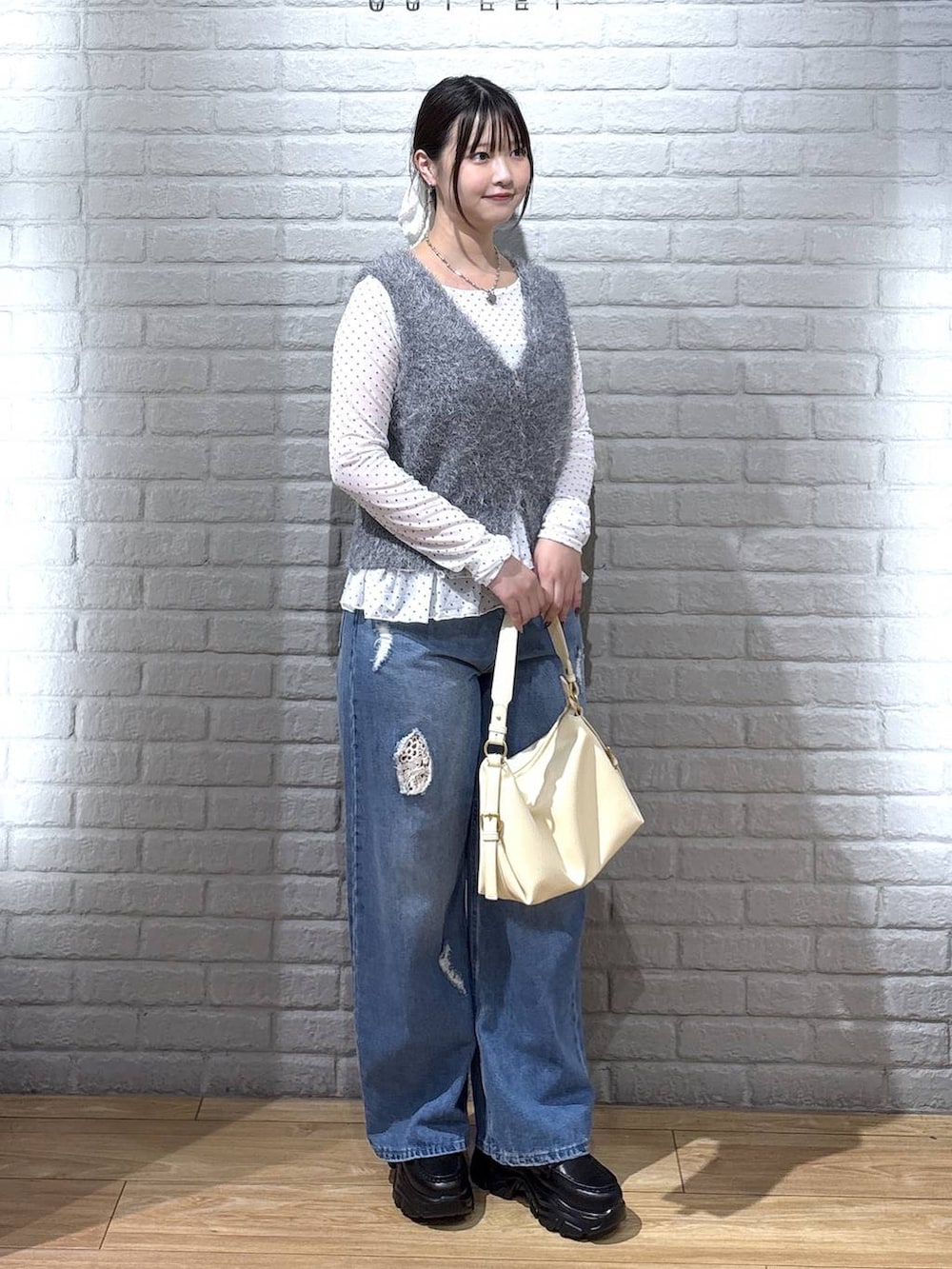 イエロー系のハンドバッグ、ホワイト系のTシャツ/カットソー、ブルー系のデニムパンツを着用したレディースの秋コーディネートの2枚目の写真